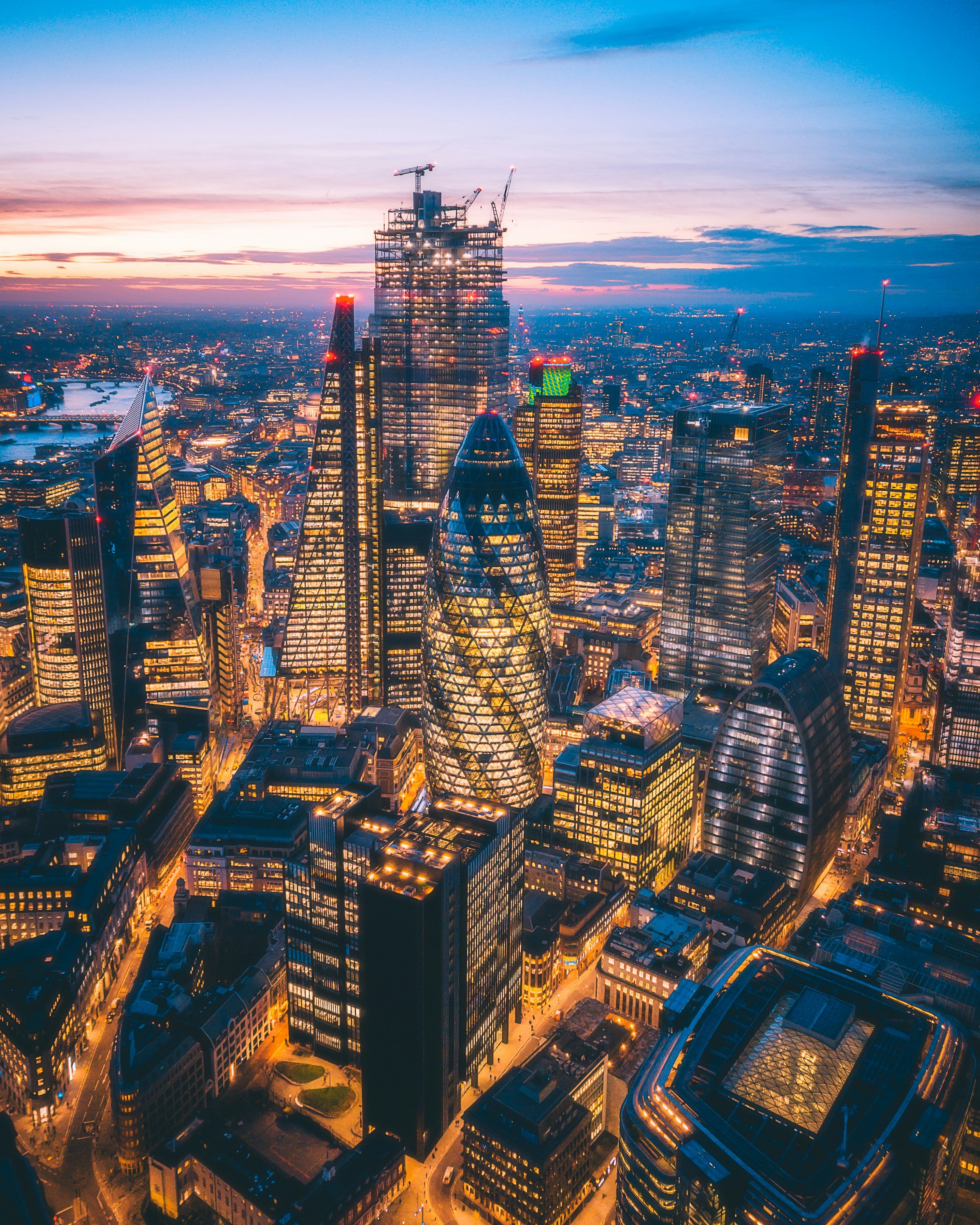 Aerial view of a London cityscape at dusk with illuminated buildings.
